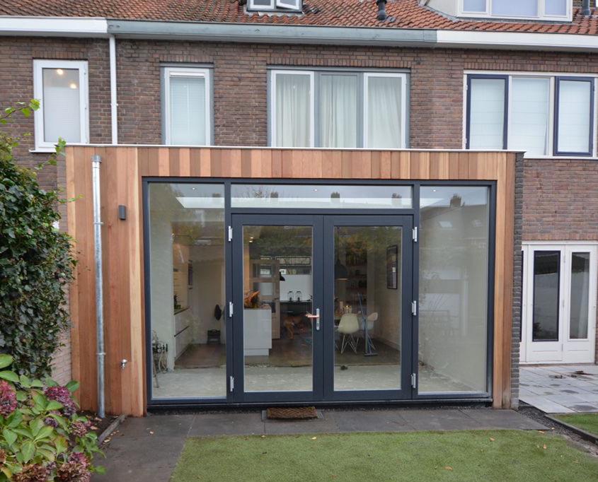 Uitbouw met houten gevelbekleding en antraciet kozijnen met openslaande deuren
